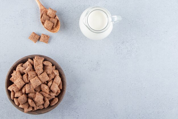 Chocolate pads cornflakes in wooden bowl with bottle of milk. High quality photo