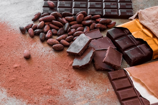 Chocolate pieces, cocoa beans and powder on table