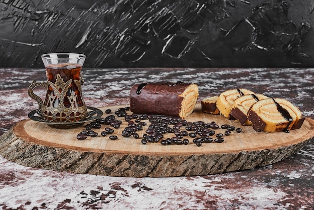 Chocolate rollcake with drink on a wooden board.