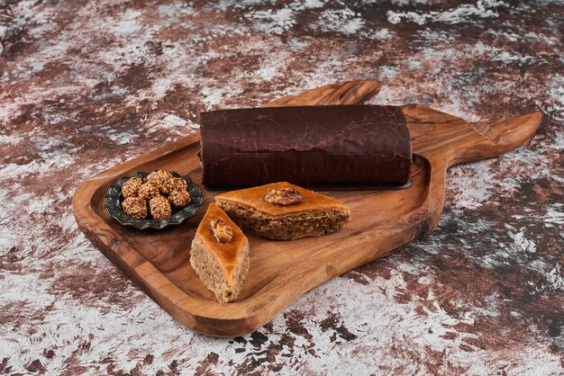 Chocolate rollcake with pakhlava on a wooden board.