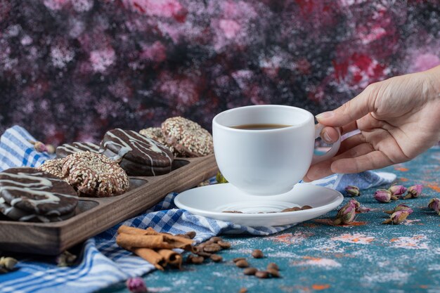 Chocolate and sesame cookies in a wooden platter with a cup of tea.