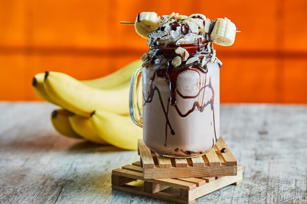 Chocolate smoothie with choco syrup and branch of bananas 