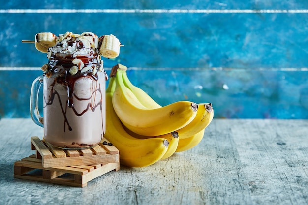 Free photo chocolate smoothie with choco syrup and branch of bananas