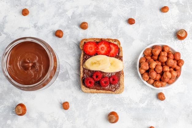 Chocolate spread or nougat cream with hazelnuts in glass jar on concrete ,  copyspace