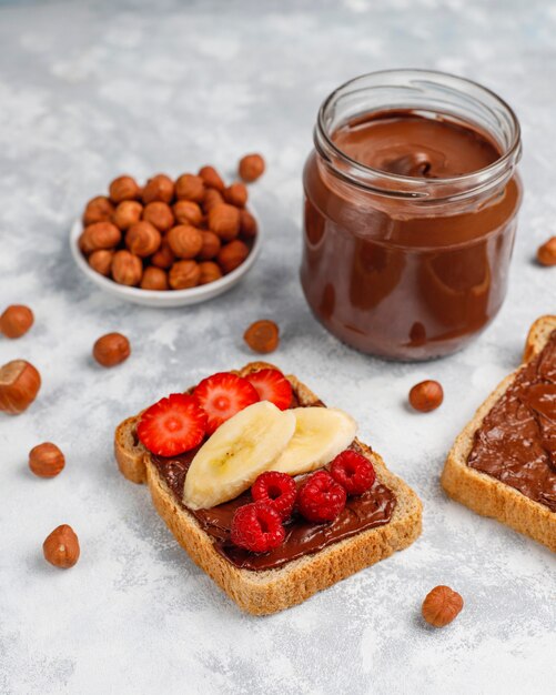 Chocolate spread or nougat cream with hazelnuts in glass jar on concrete ,  copyspace