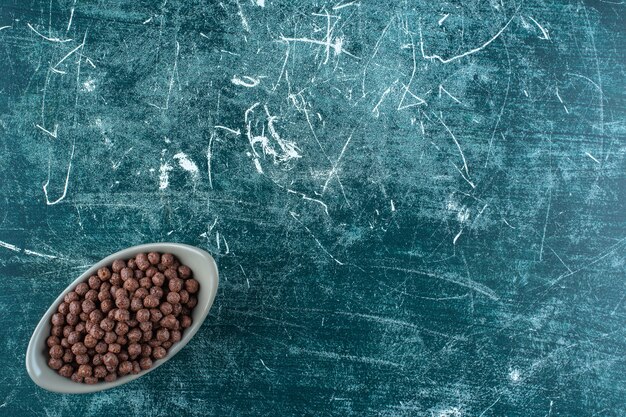 Chocolate sweet corn balls in a bowl , on the blue background. High quality photo