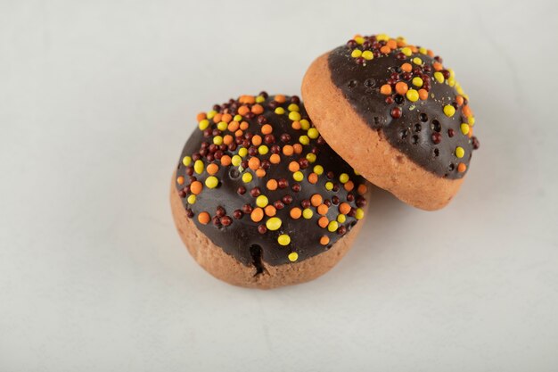 Chocolate sweet doughnuts with colorful sprinkles .