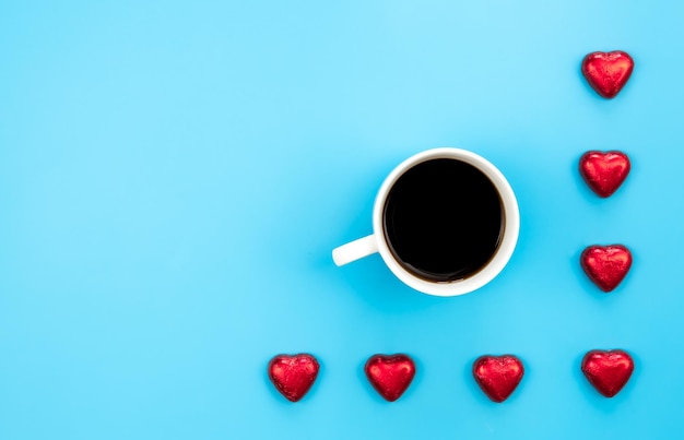 Free photo chocolate sweets in the form of hearts and a cup of coffee on a blue background