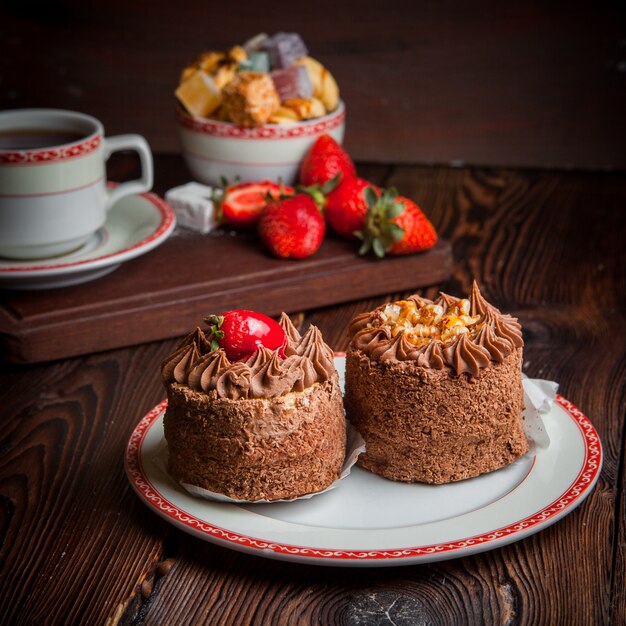 chocolate tarts with strawberry and sugar and cup of tea in plate