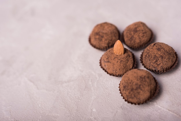 Chocolate truffle with almond on white concrete textured backdrop