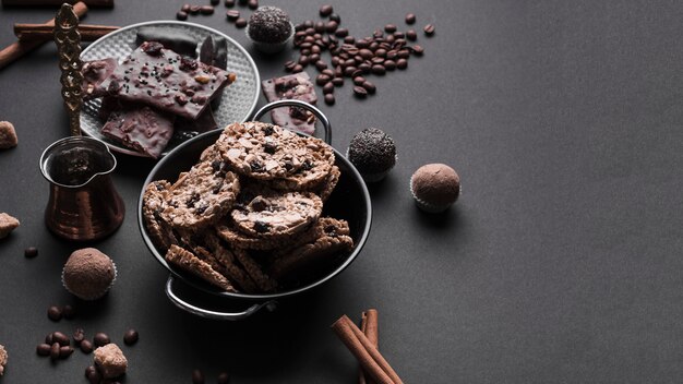 Chocolate truffles and healthy oats cookies in utensil on black backdrop