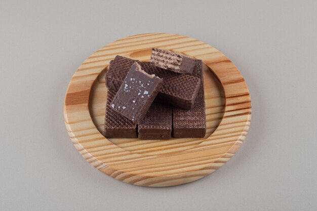 Chocolate wafers bundled together on a wooden platter on marble background.