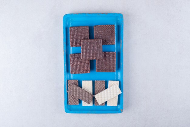 Chocolate wafers on a wooden plate on marble table.
