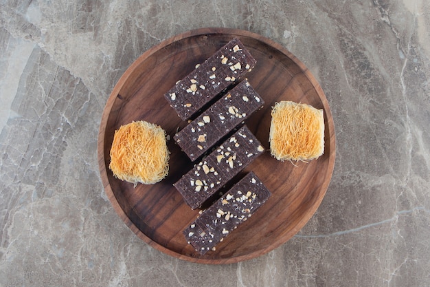 Chocolate waffle and kadayif on a wooden plate on marble.