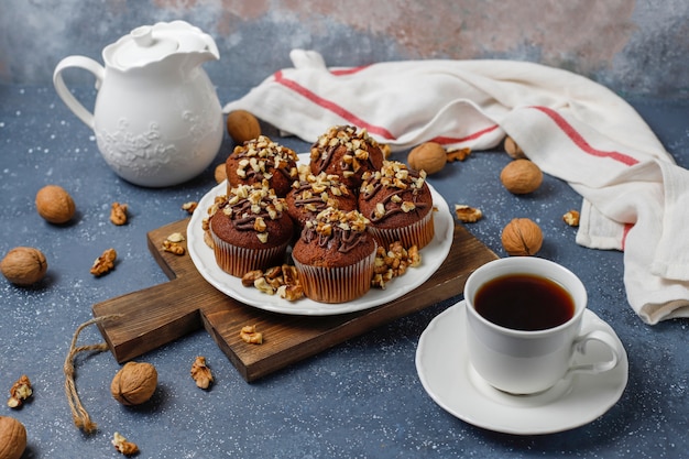 Chocolate-walnut muffins with coffee cup with walnuts on dark surface 