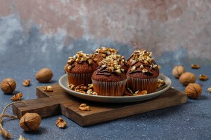chocolate-walnut muffins with coffee cup with walnuts on dark surface 
