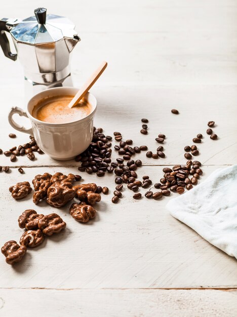 Noce di cioccolato; chicchi di caffè tostato e caffè espresso sul tavolo di legno