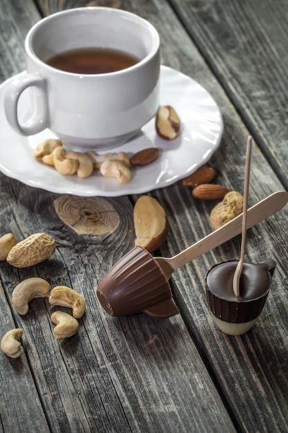 Chocolates with tea and nuts on wooden background