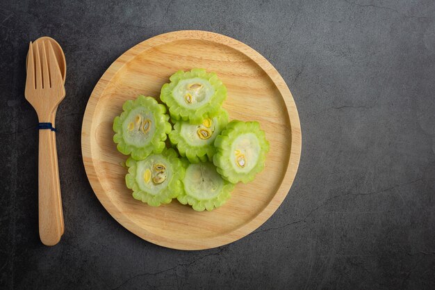 chopped bitter gourd put on wooden plate with spoon and fork