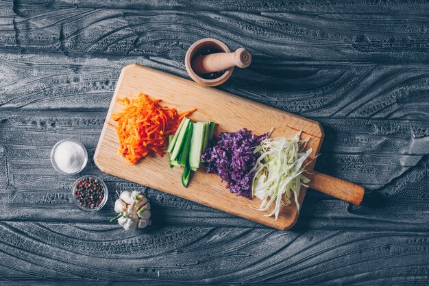 Chopped cabbage on a cutting board with other vegetables top view on a dark wooden background