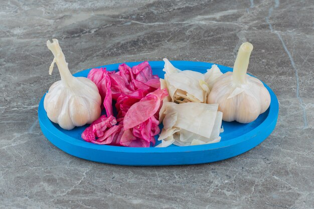 Chopped cabbage and gallic pickle on blue wooden plate. 