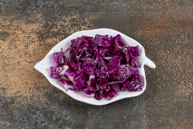 Chopped cabbage in a leaf-shaped plate, on the marble surface