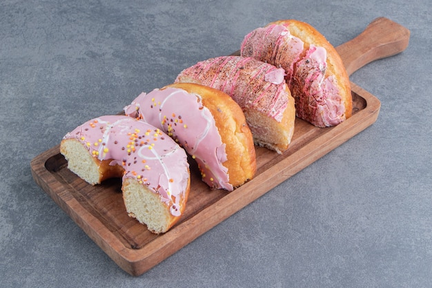 Chopped cake with pink frosting on a wooden board