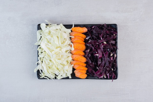 Free photo chopped carrots, red and white cabbage on black plate. high quality photo