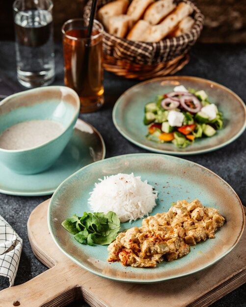 Chopped chicken breast prepared with sauce and served with rice salad and soup