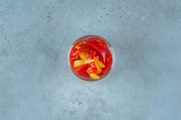 Chopped multicolor bell peppers in a glass cup.