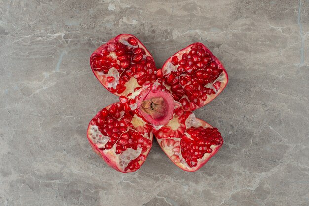 Chopped pomegranates and seeds on marble table.