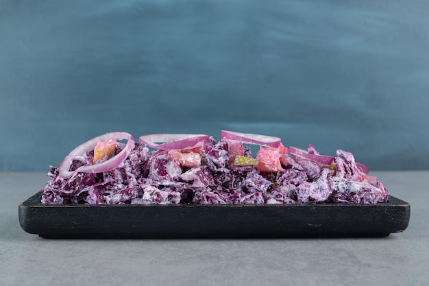 Chopped purple onion and cabbage salad in a platter on the concrete table.