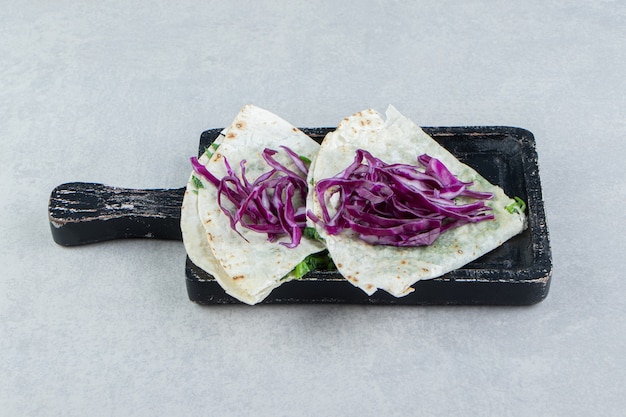 Chopped red cabbage and gutabs on the tray, on the marble background.