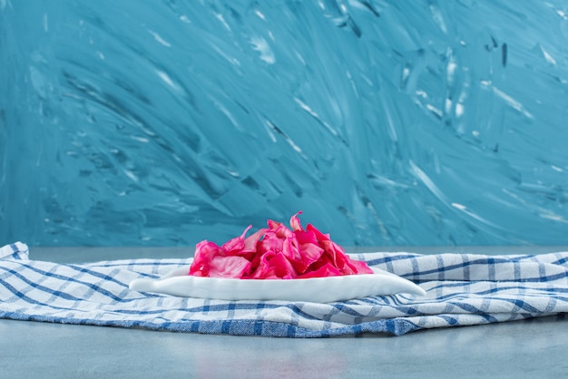 Chopped red fermented sauerkraut in a bowl on a trivet , on the blue table. 