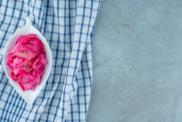 Chopped red fermented sauerkraut in a bowl on a trivet , on the blue table. 