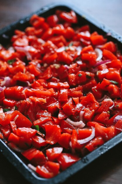 Chopped red tomatoes with herbs in a black pan