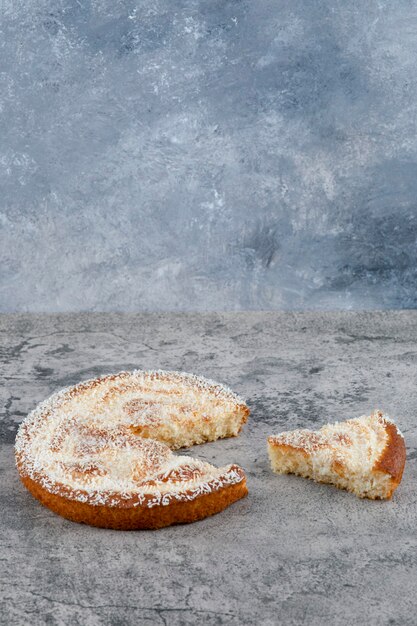 Chopped round delicious cake placed on a marble table.