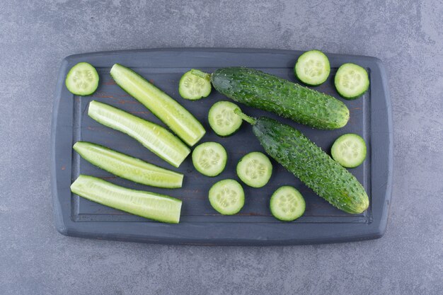 Chopped and sliced green cucumbers on a wooden board