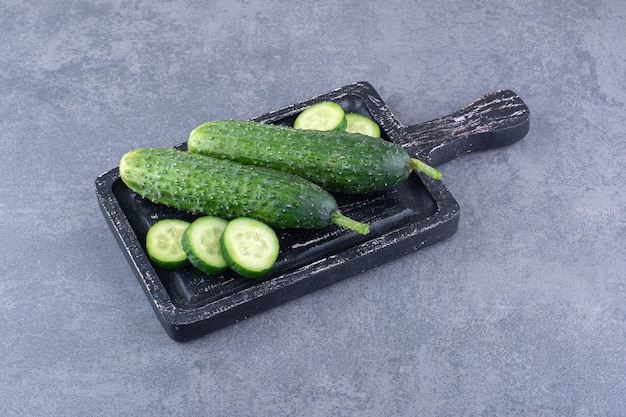 Chopped and sliced green cucumbers on a wooden board