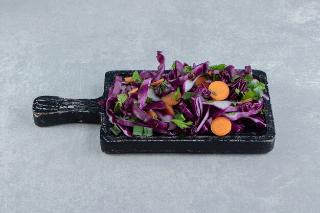 Салат из рубленых овощей на деревянной доске, на мраморе.