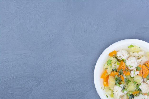 Chopped vegetables in a broth soup in a white plate