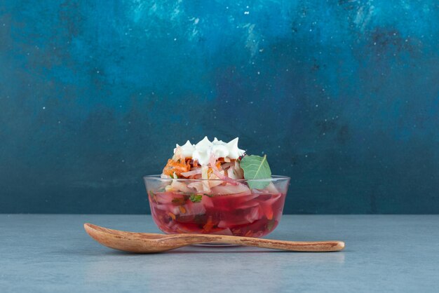 Chopped vegetables in glass bowl with spoon.