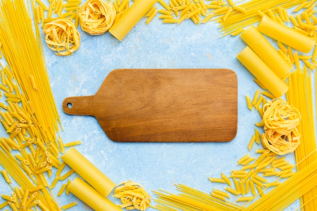 Free photo chopping board surrounded by pasta