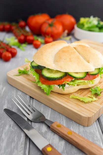 Chopping board with sandwich on top and tomatoes