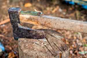 Free photo chopping wood with ax. ax stuck in a log of wood. old, worn, scratched, sharp ax standing on a wooden, cracked tree stump on a background of chopped wood.