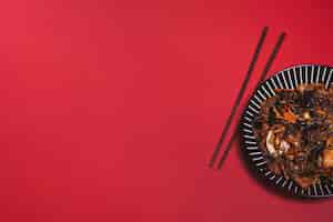 Foto gratuita bacchette e piatto asiatico sul rosso