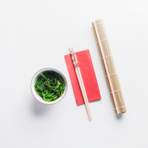 Chopsticks between bamboo napkin and seaweed salad