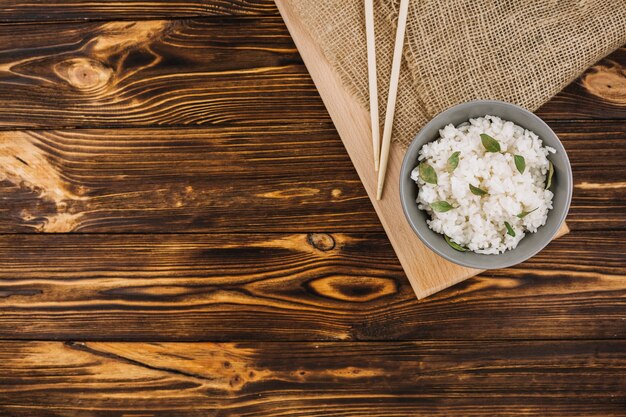 Chopsticks and bowl on board and linen cloth