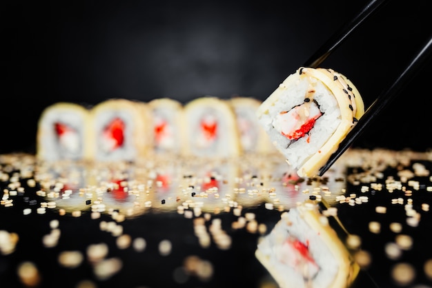 Chopsticks holding roll made of Nori, Marinated rice, Philadelphia, Cheese