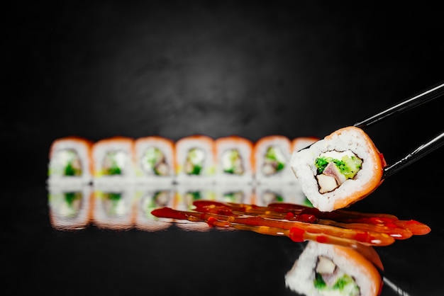 Free photo chopsticks holding sushi roll red dragon made of smoked salmon, nori